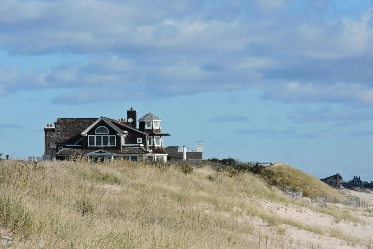 Cedar-shingled house above the dunes under a summer sky